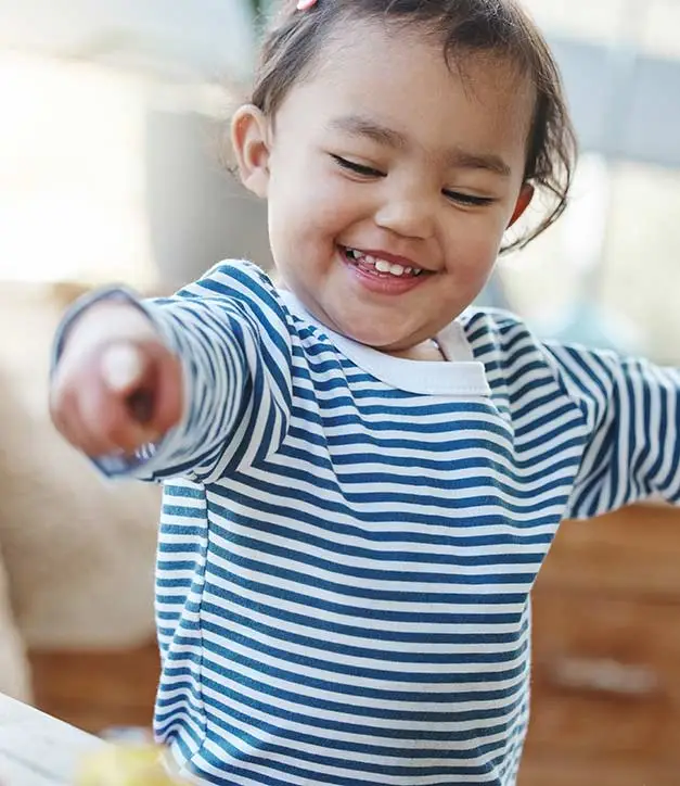 Happy toddler pointing daycare toys.