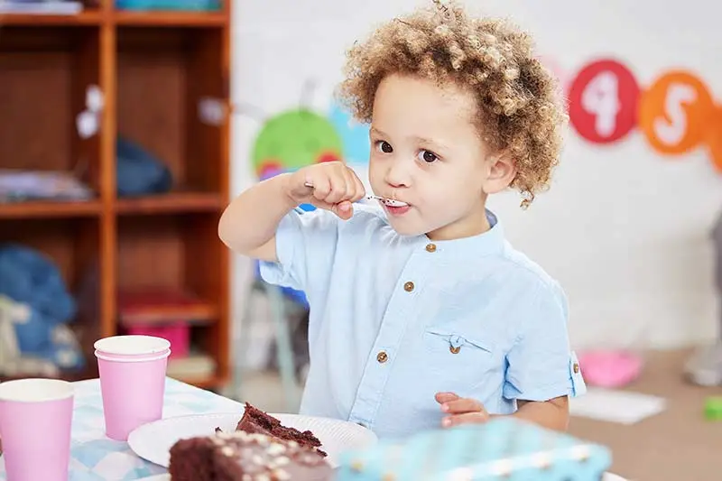 A toddler eating lunch in a daycare classroom.